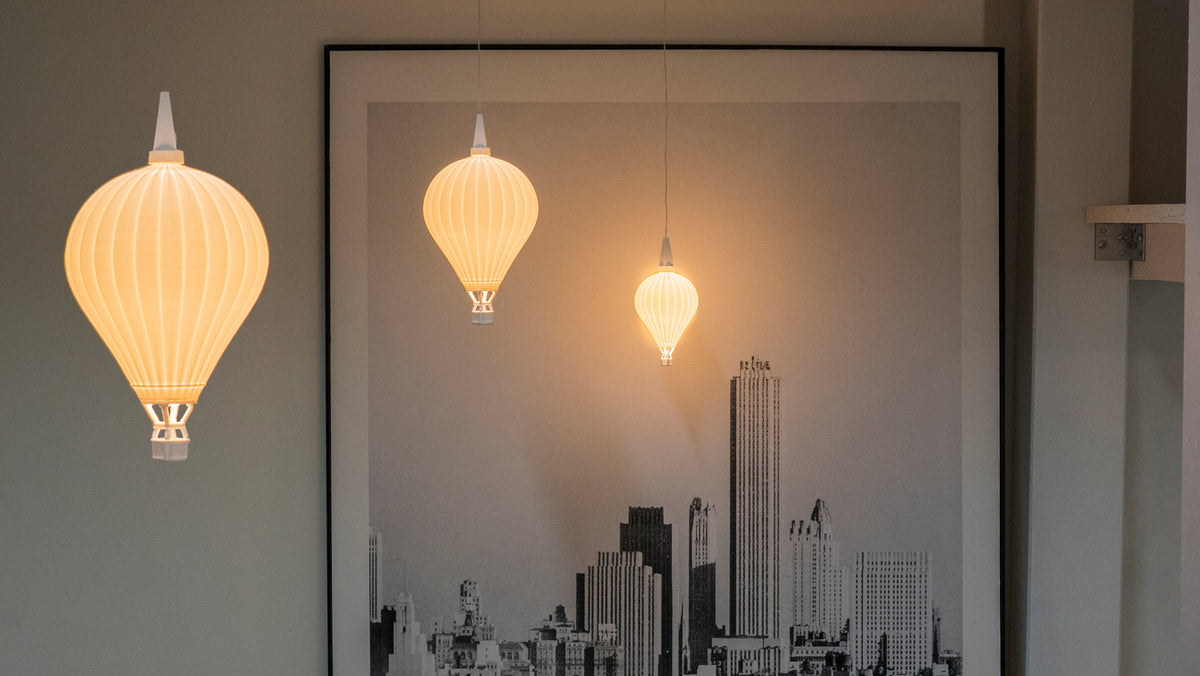 Drei beleuchtete Heißluftballon-Lampenschirme von Benago Lights in verschiedenen Größen vor dunkler Wand