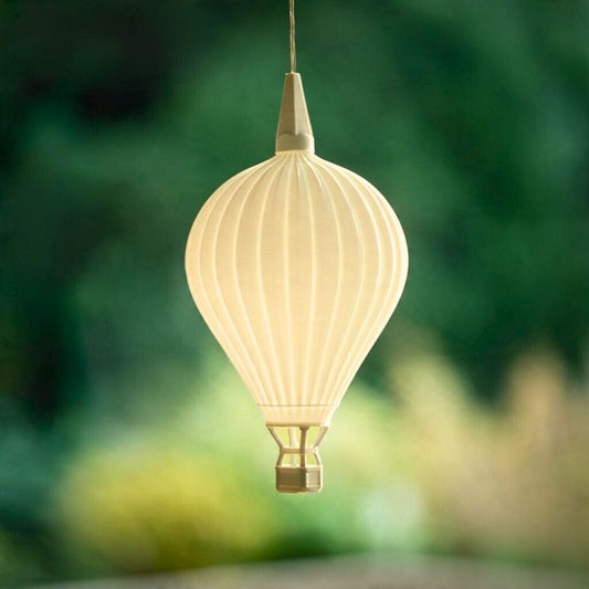 Leuchtender Heißluftballon-Lampenschirm von Benago Lights hängt an einem Kabel vor unscharfem grünem Hintergrund