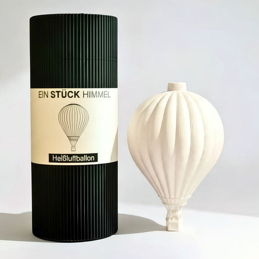 Weißer Heißluftballon-Lampenschirm von Benago Lights neben der schwarzen Geschenkverpackung „Ein Stück Himmel“