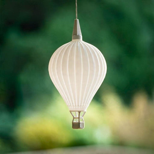 Weißer Heißluftballon-Lampenschirm hängt ausgeschaltet an einem Kabel vor grünem Hintergrund