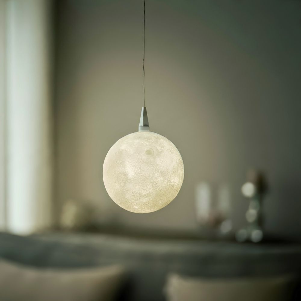 Leuchtender Lampenschirm The Moon von Benago Lights hängt an einem dünnen Kabel in einem Wohnraum mit gedämpftem Licht