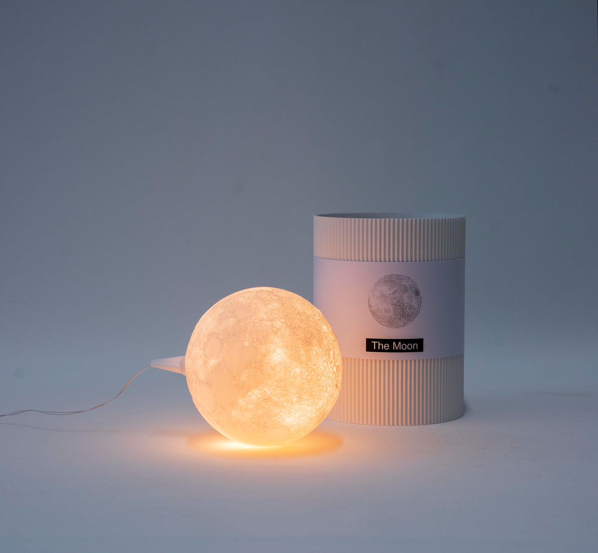 Leuchtender Mond-Lampenschirm The Moon von Benago Lights neben seiner Verpackung